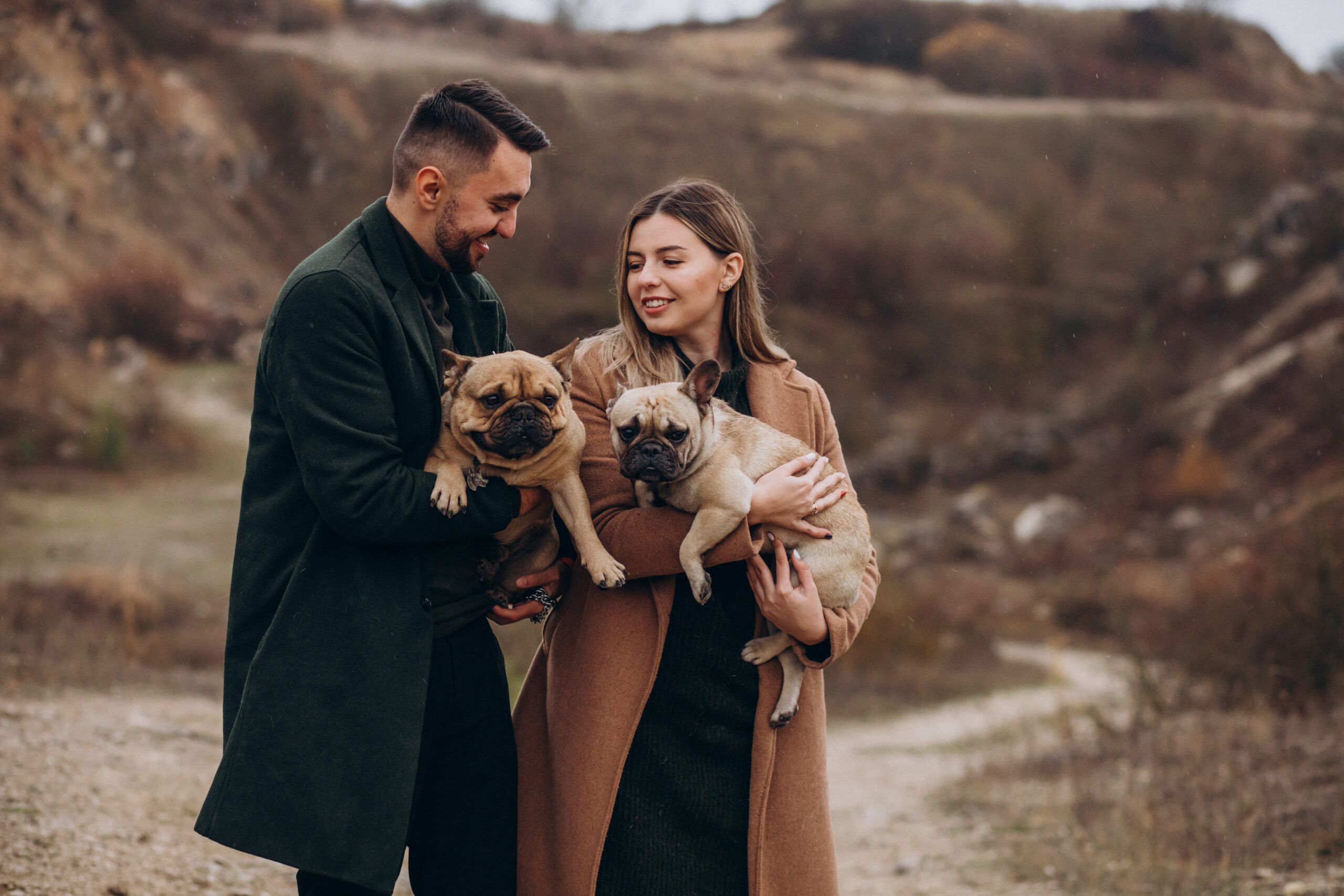 Young couple walking their french bulldogs in park
